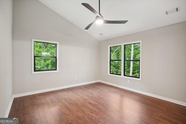 empty room featuring visible vents, baseboards, vaulted ceiling, dark wood-style floors, and a ceiling fan