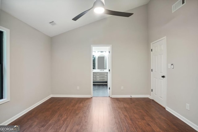 spare room featuring dark wood-style floors, baseboards, visible vents, ceiling fan, and vaulted ceiling