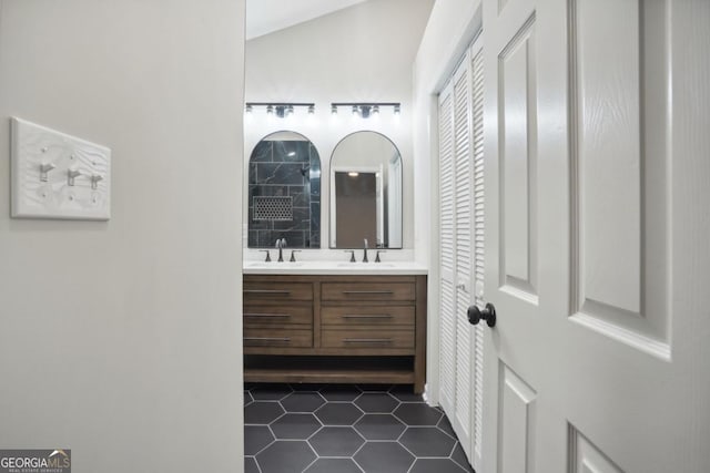 full bath with a sink, a tile shower, double vanity, and tile patterned floors