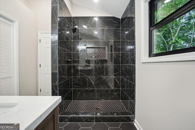 bathroom featuring vanity, vaulted ceiling, and a walk in shower