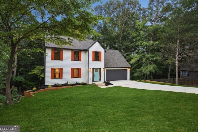 colonial inspired home with fence, concrete driveway, a front yard, a shingled roof, and an attached garage