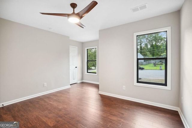 spare room featuring dark wood-type flooring, baseboards, visible vents, and ceiling fan