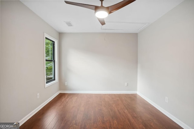 unfurnished room with visible vents, a ceiling fan, wood finished floors, baseboards, and attic access