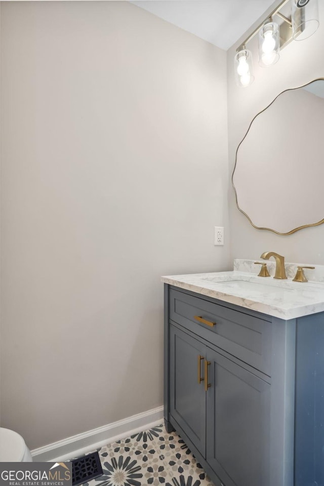 half bathroom with baseboards, toilet, and vanity