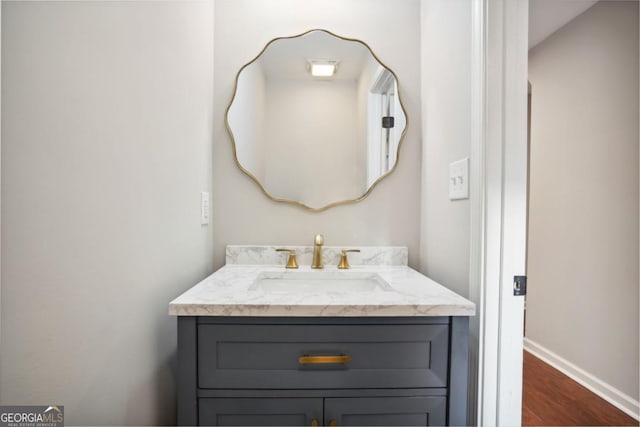 bathroom with vanity, wood finished floors, and baseboards