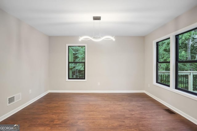 empty room with a notable chandelier, visible vents, and a wealth of natural light