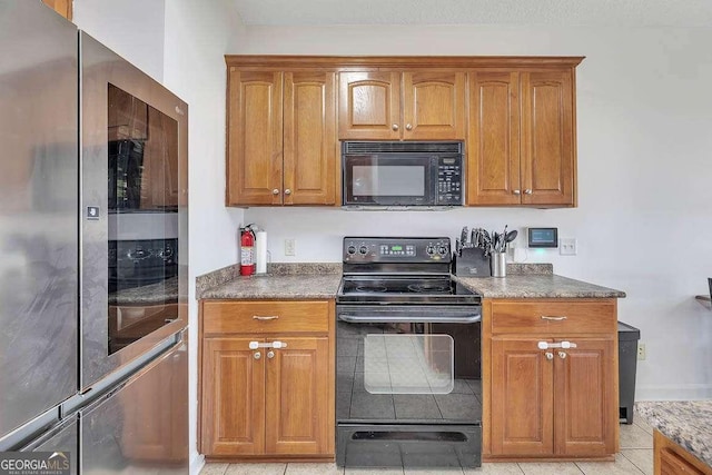 kitchen featuring black appliances, dark countertops, and brown cabinetry