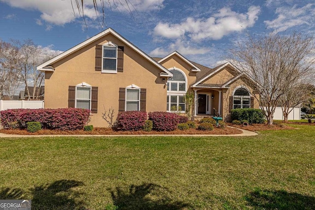 view of front of home with a front yard, fence, and stucco siding