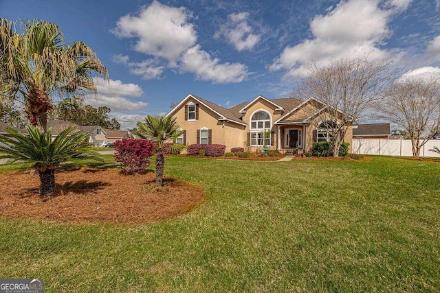 view of front of house featuring a front lawn, fence, and stucco siding