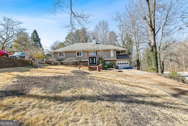 view of front of property with a garage, a chimney, and driveway