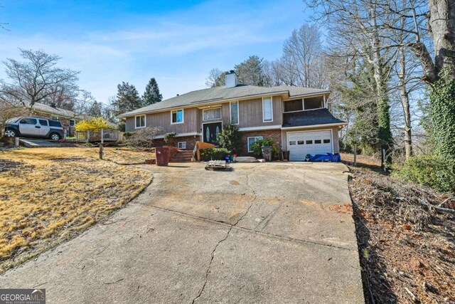 raised ranch with driveway, a chimney, and a garage