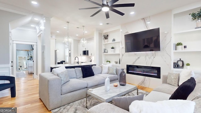 living area featuring built in features, a ceiling fan, a premium fireplace, light wood-style flooring, and recessed lighting