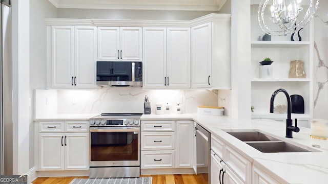 kitchen with a sink, open shelves, white cabinetry, stainless steel appliances, and an inviting chandelier