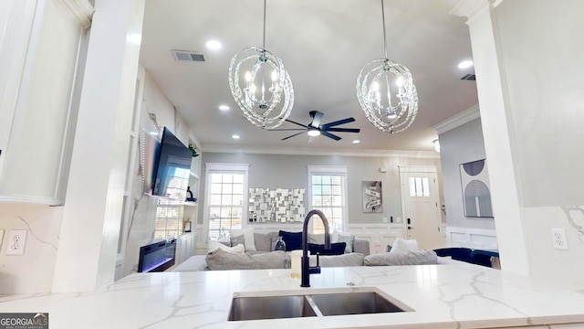 kitchen with visible vents, ceiling fan with notable chandelier, a sink, open floor plan, and crown molding