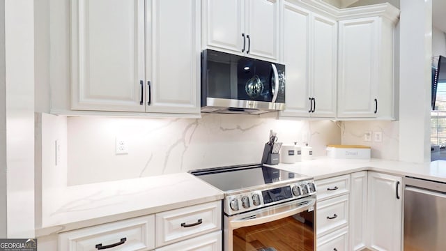 kitchen featuring white cabinets, light stone countertops, tasteful backsplash, and stainless steel appliances