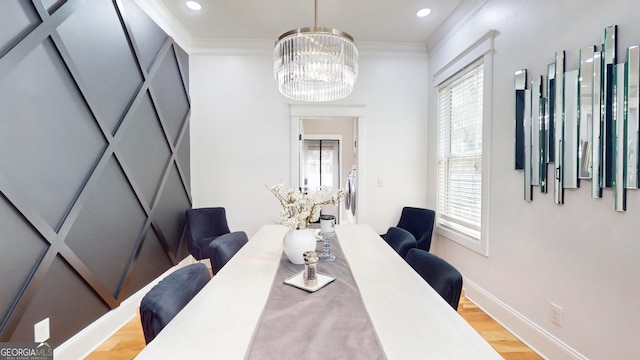 dining area featuring light wood-style floors, baseboards, a chandelier, and ornamental molding