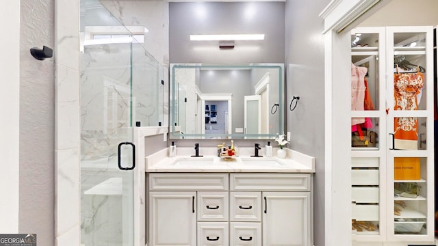 bathroom with a marble finish shower, double vanity, and a sink