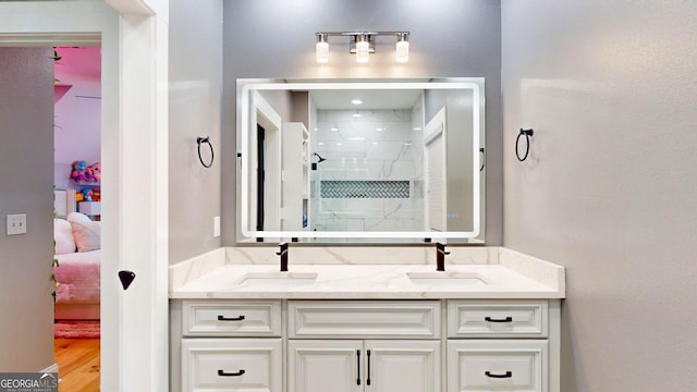 full bathroom with a sink, double vanity, and a shower stall