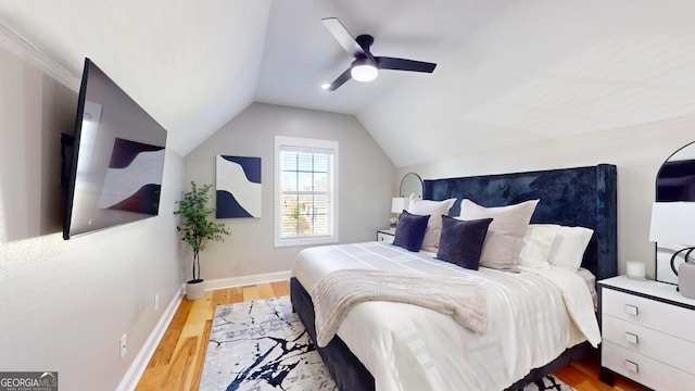 bedroom with a ceiling fan, vaulted ceiling, light wood-style floors, and baseboards