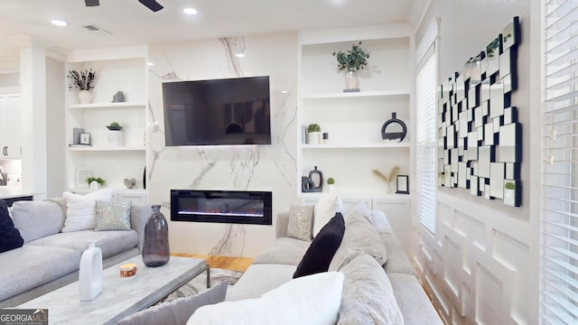 living room with visible vents, built in shelves, ceiling fan, a premium fireplace, and recessed lighting