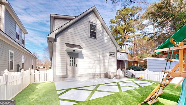 back of house featuring a playground, a patio area, a lawn, and a fenced backyard