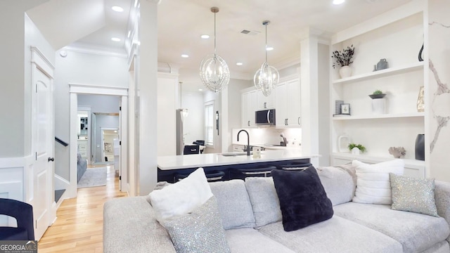 living area with visible vents, ornamental molding, built in features, recessed lighting, and light wood-style floors