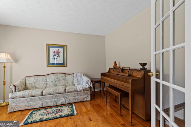 living room featuring a textured ceiling, baseboards, and wood finished floors