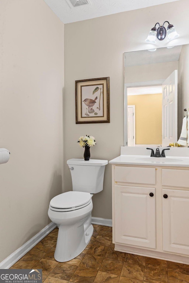 half bathroom with vanity, toilet, and baseboards