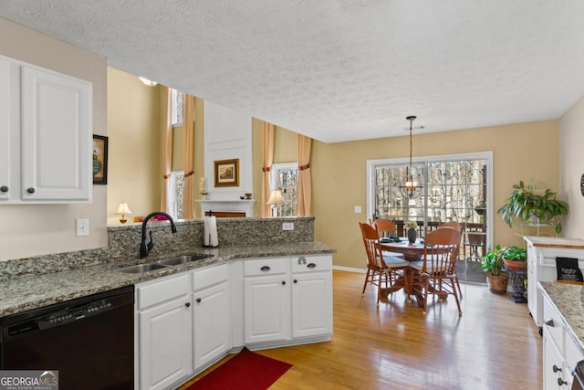 kitchen with a sink, black dishwasher, white cabinetry, a peninsula, and light wood finished floors