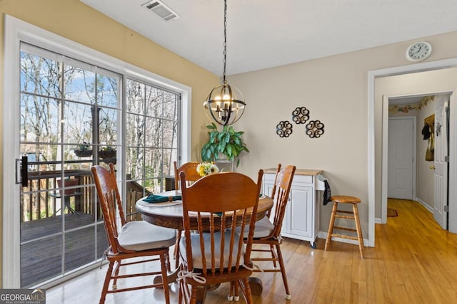 dining area featuring a notable chandelier, baseboards, visible vents, and light wood-type flooring