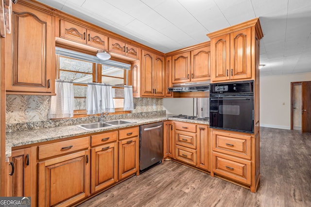 kitchen with a sink, appliances with stainless steel finishes, wood finished floors, and under cabinet range hood