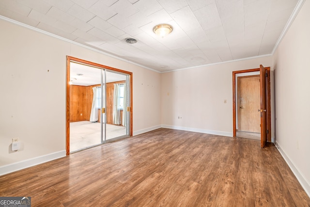 spare room featuring visible vents, ornamental molding, baseboards, and wood finished floors