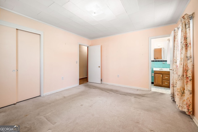 unfurnished bedroom with connected bathroom, baseboards, light colored carpet, and a closet