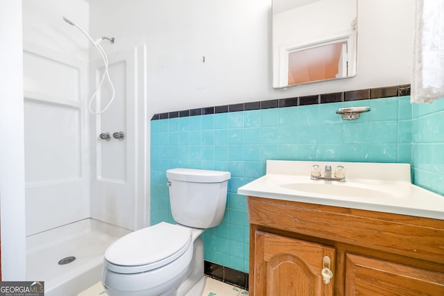 bathroom with a shower stall, tile walls, a wainscoted wall, toilet, and vanity