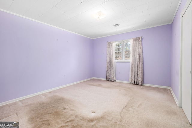 carpeted empty room featuring baseboards and ornamental molding