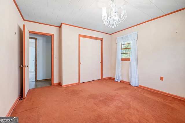 unfurnished bedroom featuring baseboards, carpet floors, ornamental molding, a closet, and a chandelier