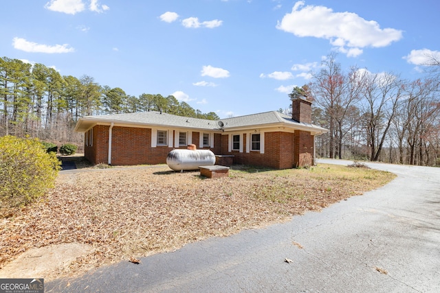 single story home featuring brick siding and a chimney