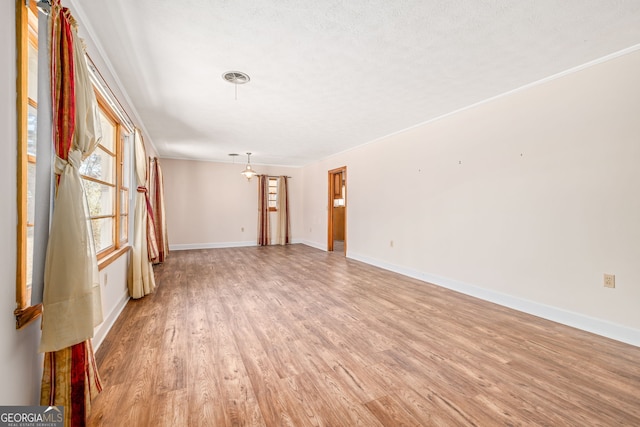 unfurnished room with light wood finished floors, a textured ceiling, and baseboards