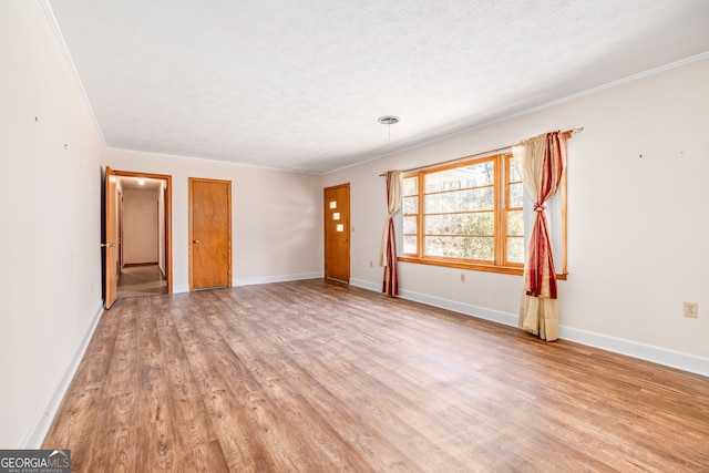 unfurnished living room with ornamental molding, baseboards, light wood-type flooring, and a textured ceiling