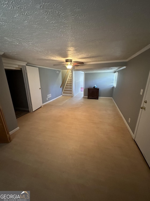 below grade area with stairs, a ceiling fan, baseboards, and a textured ceiling