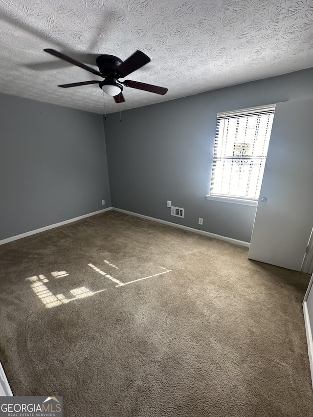 carpeted spare room featuring visible vents, a textured ceiling, baseboards, and ceiling fan