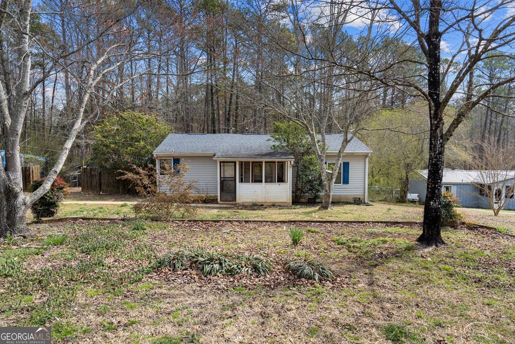 ranch-style home featuring a front lawn and roof with shingles