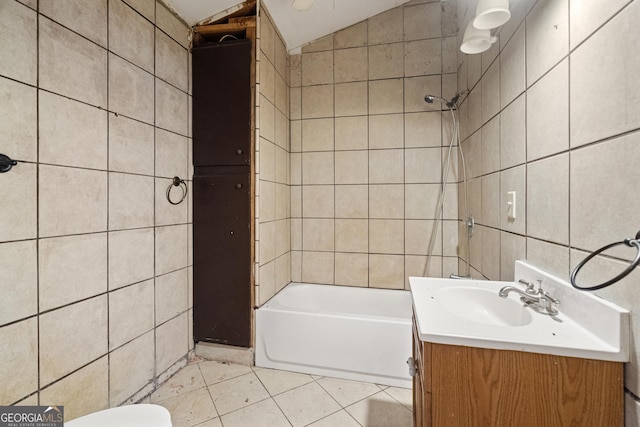 bathroom featuring vanity, shower / bathing tub combination, vaulted ceiling, tile walls, and tile patterned floors