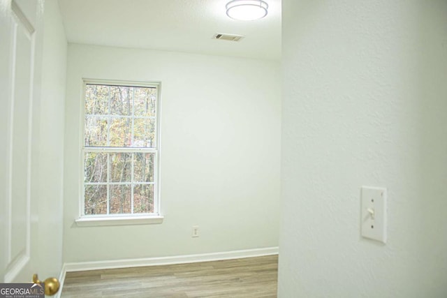 spare room featuring visible vents, baseboards, and wood finished floors