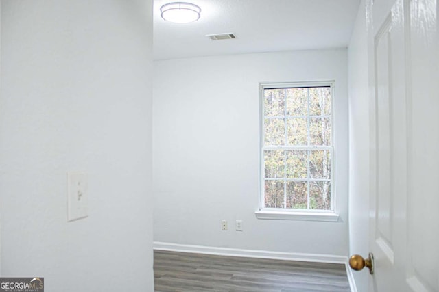 empty room with wood finished floors, baseboards, and visible vents