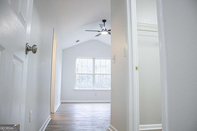 hall featuring baseboards, lofted ceiling, and wood finished floors