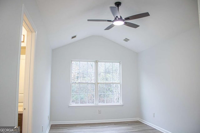 unfurnished bedroom featuring visible vents, wood finished floors, baseboards, and vaulted ceiling