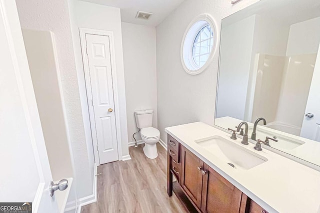 full bath with visible vents, toilet, wood finished floors, baseboards, and vanity