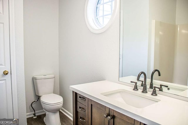 bathroom featuring vanity, toilet, wood finished floors, and baseboards