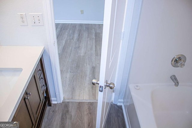 bathroom featuring vanity, wood finished floors, baseboards, and bathtub / shower combination